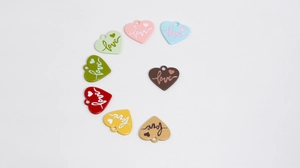 Macro shot of 8 colorful alloy heart charms with love engraving for DIY jewelry making