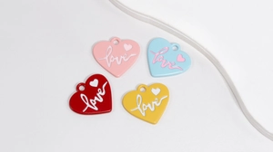 Close-up of four colorful heart pendants with love engraving for DIY jewelry