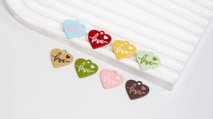 Macro shot of colorful alloy heart pendants with Love engraving for DIY jewelry