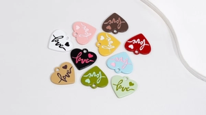 Flat lay of colorful heart alloy pendants with Love engraving for DIY jewelry