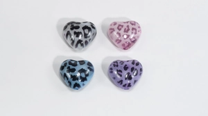 Close-up of heart-shaped acrylic leopard print beads in grey, pink, blue, and purple