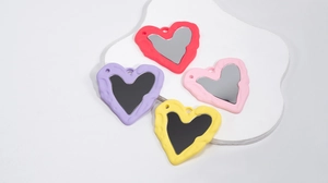 Dettaglio macro di specchi acrilici a cuore colorati con cornici ondulate e fori per appendere