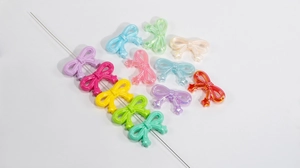 Detailed macro view of colorful acrylic bow beads with iridescent pearl finish and pre-drilled holes