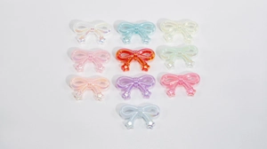 Close-up of colorful acrylic iridescent bow pendants for DIY jewelry and phone charms