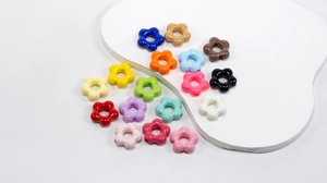 Colorful acrylic flower beads scattered on a white tray for DIY jewelry making