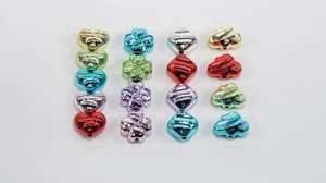 Dettaglio di perline in acrilico metallico colorato a forma di cuore, trifoglio e nuvola