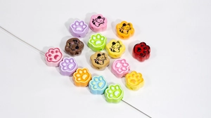 Macro view of colorful cat paw beads and kitten charms with holes for DIY jewelry