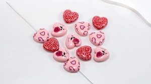 Macro shot of acrylic heart beads with Love text and rose prints for DIY jewelry