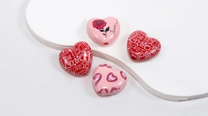 Macro detail of acrylic heart beads with Love and flower patterns for DIY jewelry making