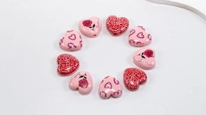 Macro shot of heart-shaped acrylic beads with rose patterns and Love lettering for DIY jewelry