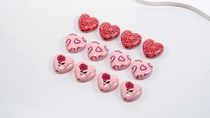 Macro shot of acrylic heart beads with Love lettering and floral patterns for DIY jewelry