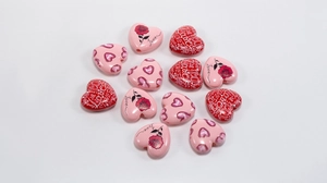 Detailed view of heart-shaped acrylic beads with floral and LOVE prints for DIY jewelry