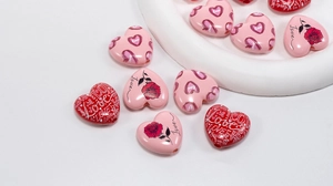 Detailed view of heart-shaped acrylic beads with rose patterns for DIY jewelry making