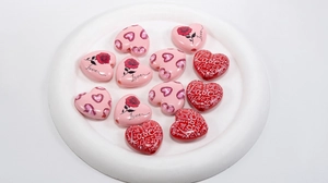 Macro view of heart-shaped acrylic beads with pink rose prints for DIY jewelry making