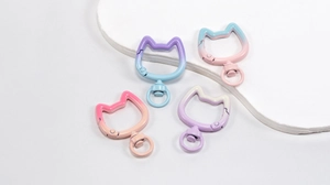 Detail of four cat-shaped metal lobster clasps with vibrant gradient paint finishes