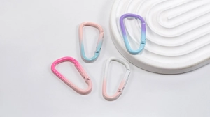 Detail of four D-shaped aluminum carabiners with vibrant gradient colors and smooth finish