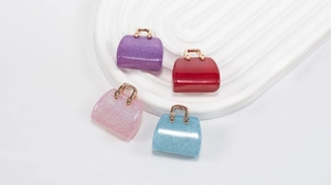 Close-up of mini acrylic handbag charms with glitter finish and gold metal handles
