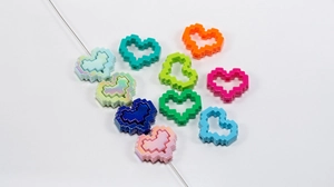 Macro shot of colorful acrylic pixel heart beads with threading holes for DIY jewelry