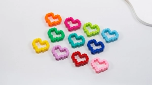 Macro detail of colorful pixel art heart acrylic beads with holes for DIY jewelry