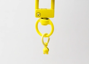 Détail d'un fermoir de porte-clés en métal jaune avec anneau rotatif et petite clochette