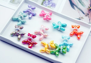 Macro view of iridescent resin balloon dog charms with pearl collars and glossy finish