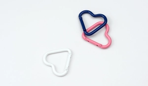 Macro detail of heart-shaped carabiners in blue, pink, and white painted metal