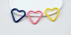 Close-up of heart-shaped alloy carabiners in blue, pink and yellow for DIY jewelry making