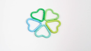 Close-up of heart-shaped alloy spring rings in various shades of green and blue