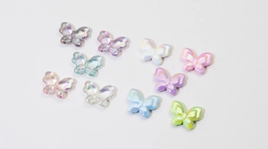 Macro-opname van 10 kleurrijke iriserende vlinderbedeltjes van hars voor DIY-sieraden