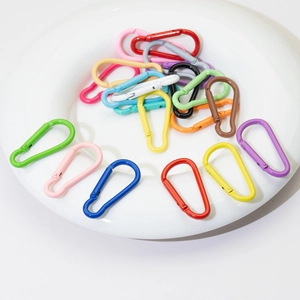 Colorful gourd-shaped alloy carabiners with spring snap hooks on a white ceramic plate