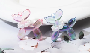 Detail of holographic balloon dog charms with pearl collars and shiny metallic coating