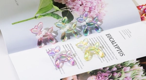 Macro detail of colorful translucent balloon dog charms with pearl collars and gold loops