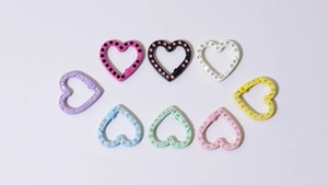 Dettaglio di moschettoni a cuore colorati con strass brillanti in otto vivaci tonalità