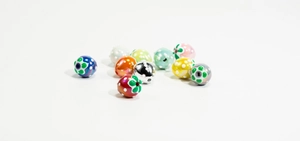Detailed view of colorful DIY strawberry beads with floral patterns and threading holes