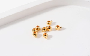 Macro shot of 18K gold-plated round crimp beads for DIY jewelry making and bracelet repair