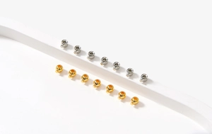 Macro detail of 18K gold and silver plated metal crimp beads for jewelry making