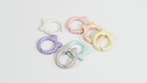 Dettaglio dei moschettoni a molla a forma di fiocco in sette colori pastello perlati