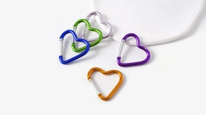 Macro shot of colorful heart-shaped carabiner clips with silver spring gates on a white tray