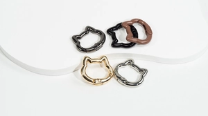 Detailed view of cat-shaped metal spring rings in gold, silver, and matte black finishes