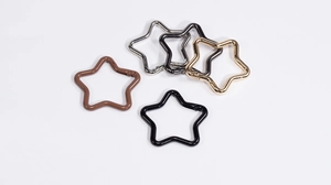 Close-up of star-shaped spring snap hooks in various metallic and matte finishes