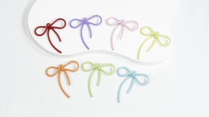 Macro detail van zeven kleurrijke legering strik hangers met textuur voor DIY sieraden