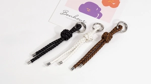 Detail of handmade braided leather keychains in black, white and brown with metal rings