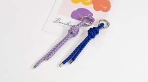 Close-up of handmade braided leather keychains in purple and blue with silver metal clips