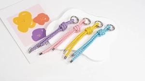 Close-up of four colorful handmade braided keychains with metallic rings and silver threads