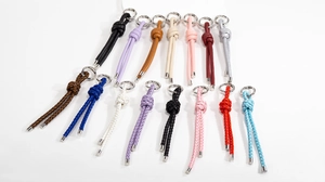 Detailed overhead view of 15 colorful braided leather keychains and bag accessories