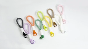 Macro shot of 9 colorful hand-woven macaron-style keychains with metal spring buckles