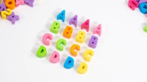 Vista macro di perle colorate con lettere in acrilico e fori per gioielli fai da te
