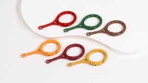 Close-up of tennis racket shaped alloy spring snap hooks in six assorted metallic colors