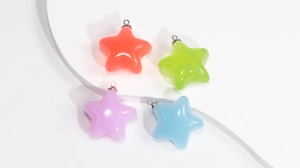Détail de quatre breloques étoiles translucides colorées avec anneaux argentés pour bijoux