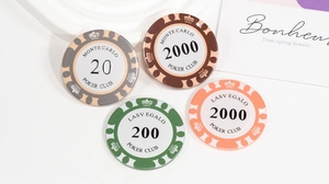 Flat lay di fiches da poker in acrilico Monte Carlo su un vassoio bianco con cartolina